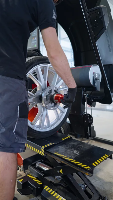 AutoLAB darbuotojas tvirtina ratą balansavimo staklėse